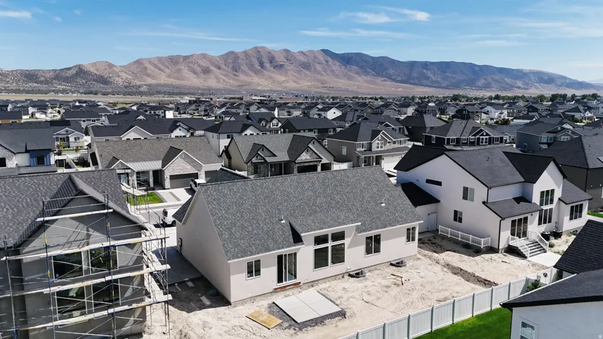 Newly constructed residence featuring a white exterior, dark shingled roof, multiple windows, and a partially fenced lot