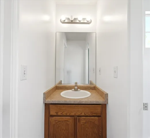 Bathroom vanity featuring a wood-finish cabinet, laminate countertop, and integrated oval sink