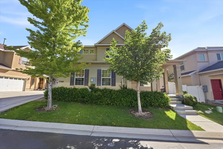 Front exterior with a covered porch, established landscaping, and a two-car garage