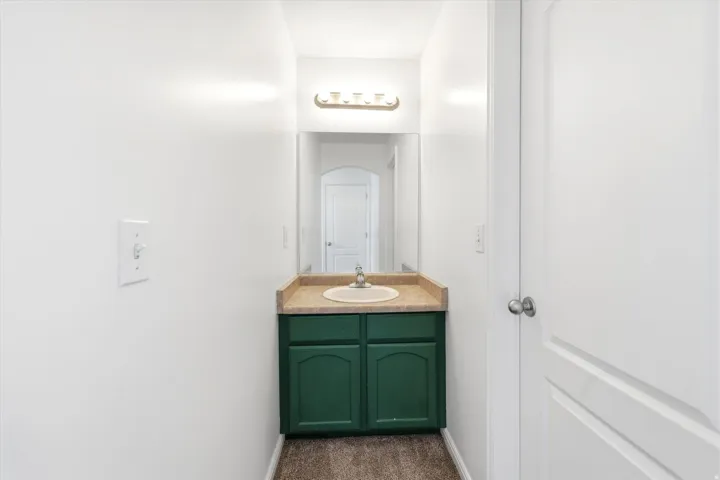 Compact vanity featuring a deep green cabinet and integrated sink