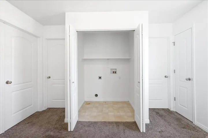 Laundry closet featuring a single shelf, utility hookups, and light-toned tile flooring