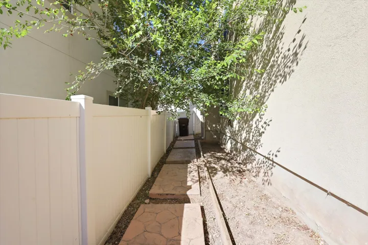 Side yard featuring a privacy fence, stepping stones, and mature foliage