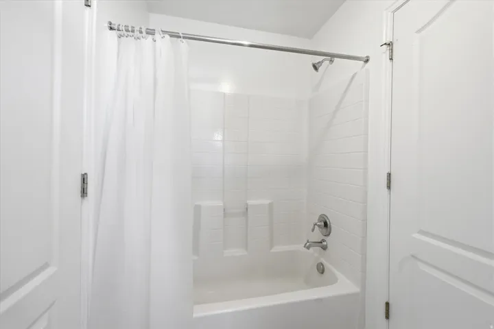 Bright white shower-over-tub combination with subway tile surround and integrated shelving