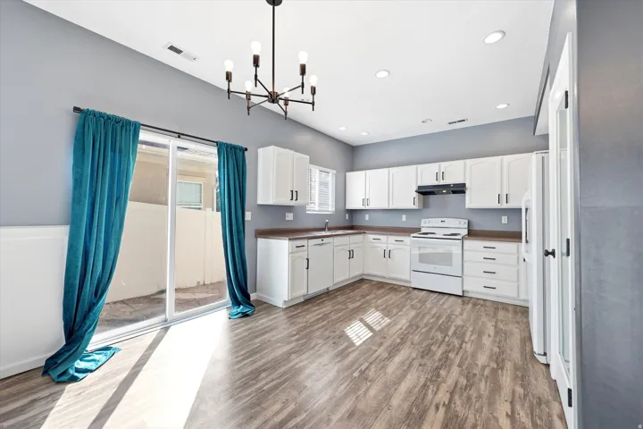 Open-concept kitchen featuring white cabinetry, modern black hardware, and wood-finish flooring
