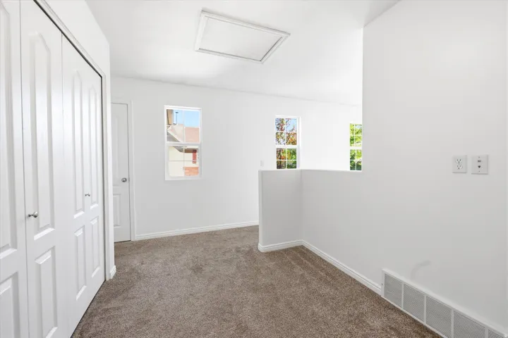 Carpeted interior space featuring white bi-fold closet doors and multiple windows