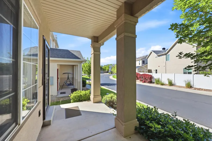 Covered porch with decorative columns, concrete flooring, and an exterior window with grid-patterned panes