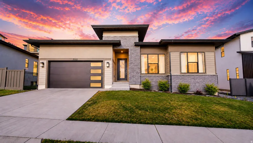 Contemporary exterior featuring a stone and stucco facade, a two-car garage with frosted glass panels, and a concrete driveway