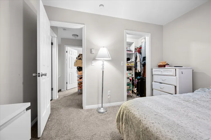 Bedroom featuring light gray wall paint, gray carpet flooring, white trim, and a built-in closet with shelving