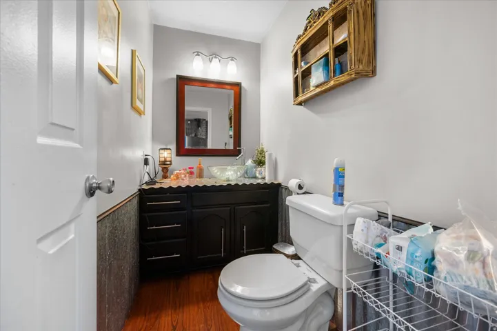 Bathroom with dark wood-finish vanity, vessel sink, and wood-finish flooring