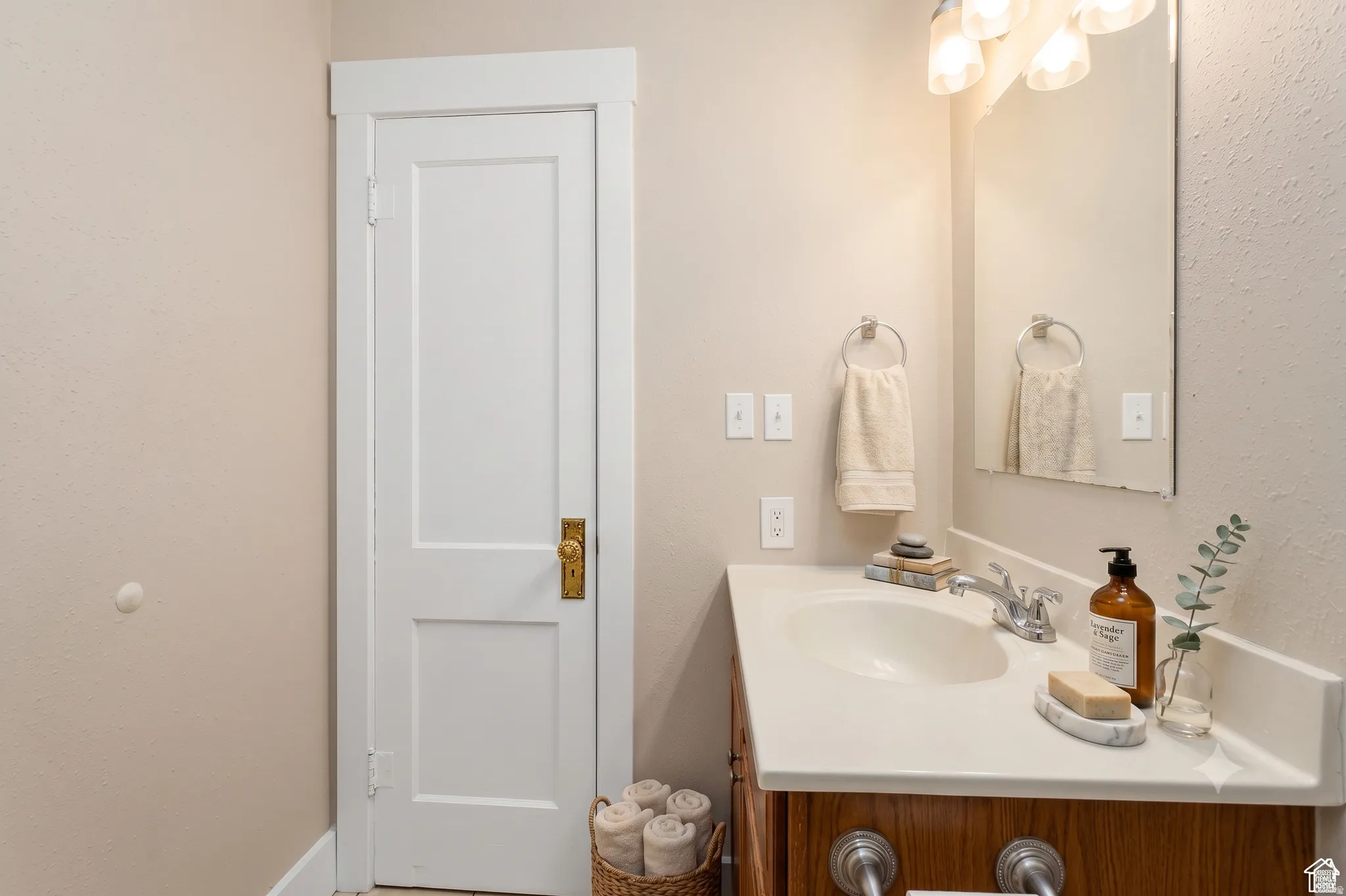 Bathroom vanity featuring a light-colored countertop with an integrated sink, metal faucet, and a wall-mounted mirror
