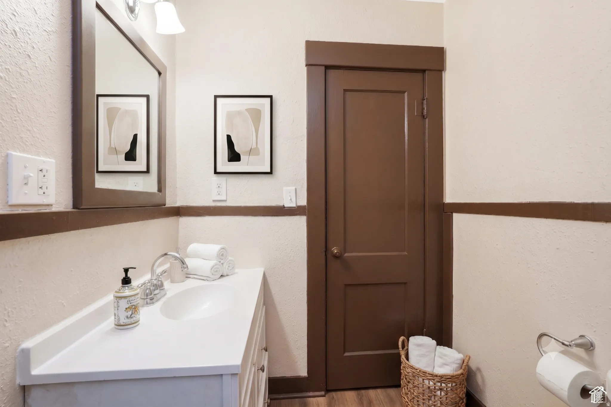 Bathroom featuring a vanity with an integrated sink, polished chrome faucet, and overhead wall-mounted lighting