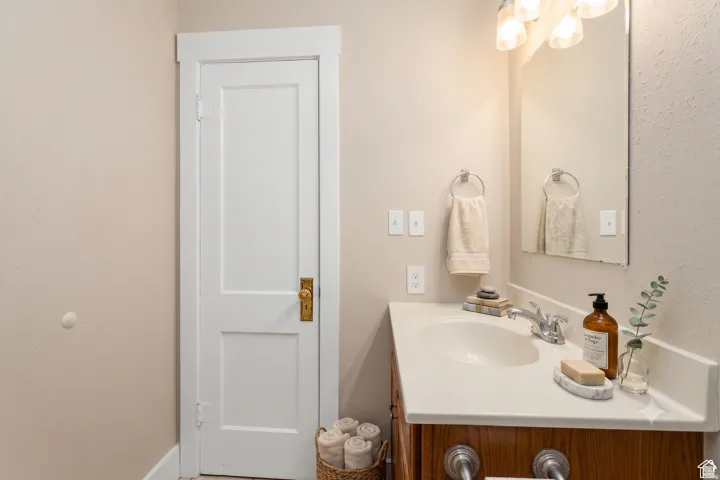 Bathroom vanity featuring a light-colored countertop with an integrated sink, metal faucet, and a wall-mounted mirror