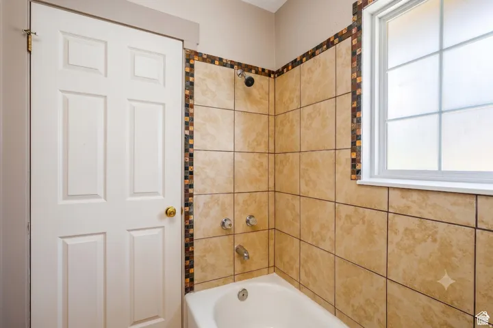 Bathtub with a tiled surround featuring decorative mosaic accents
