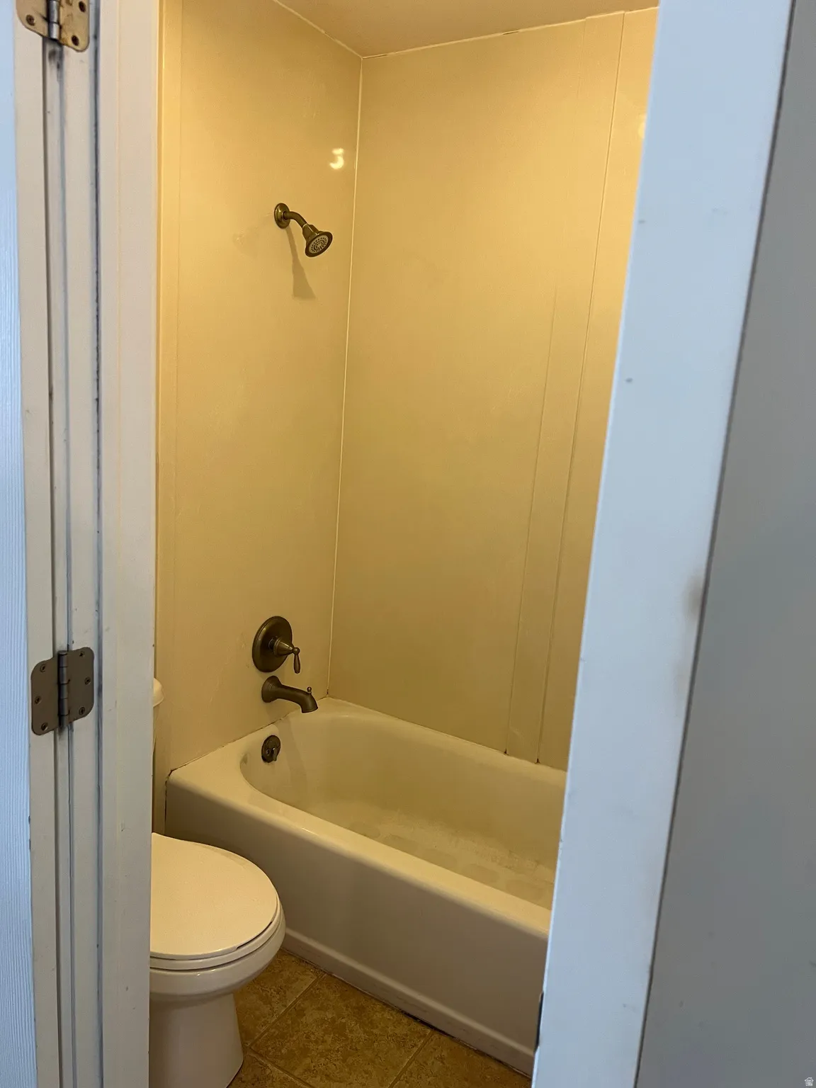 Bathroom featuring a white bathtub, bronze-finish shower fixtures, and a white toilet