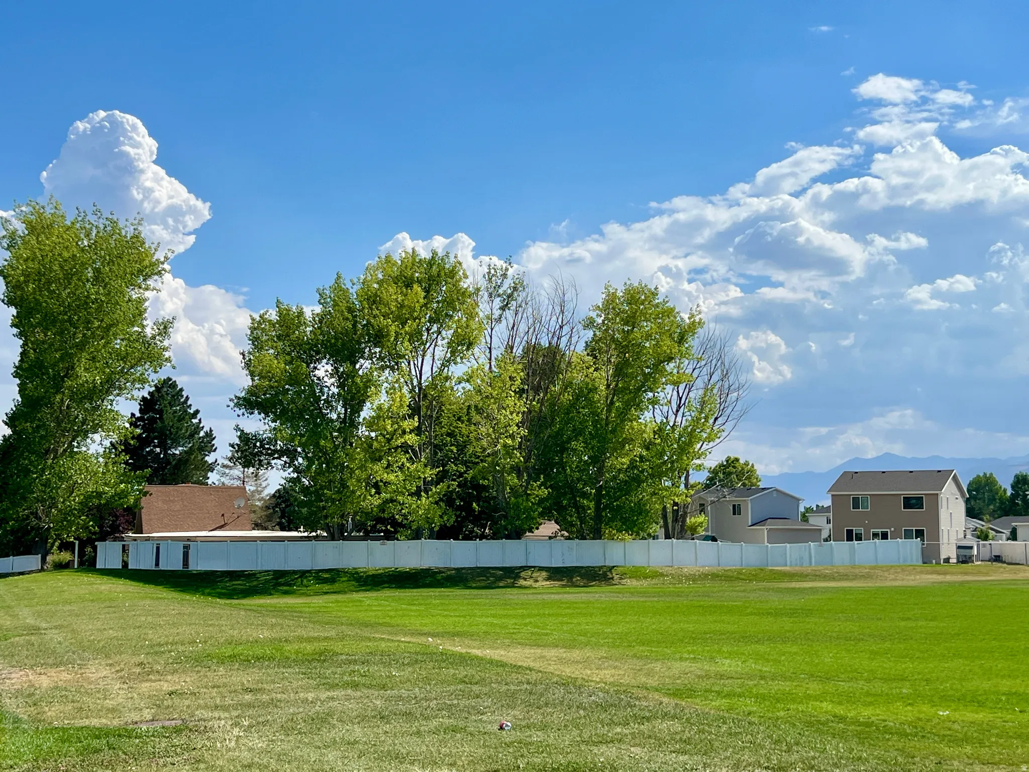 Expansive green space with distant mountain ranges and a clear sky backdrop