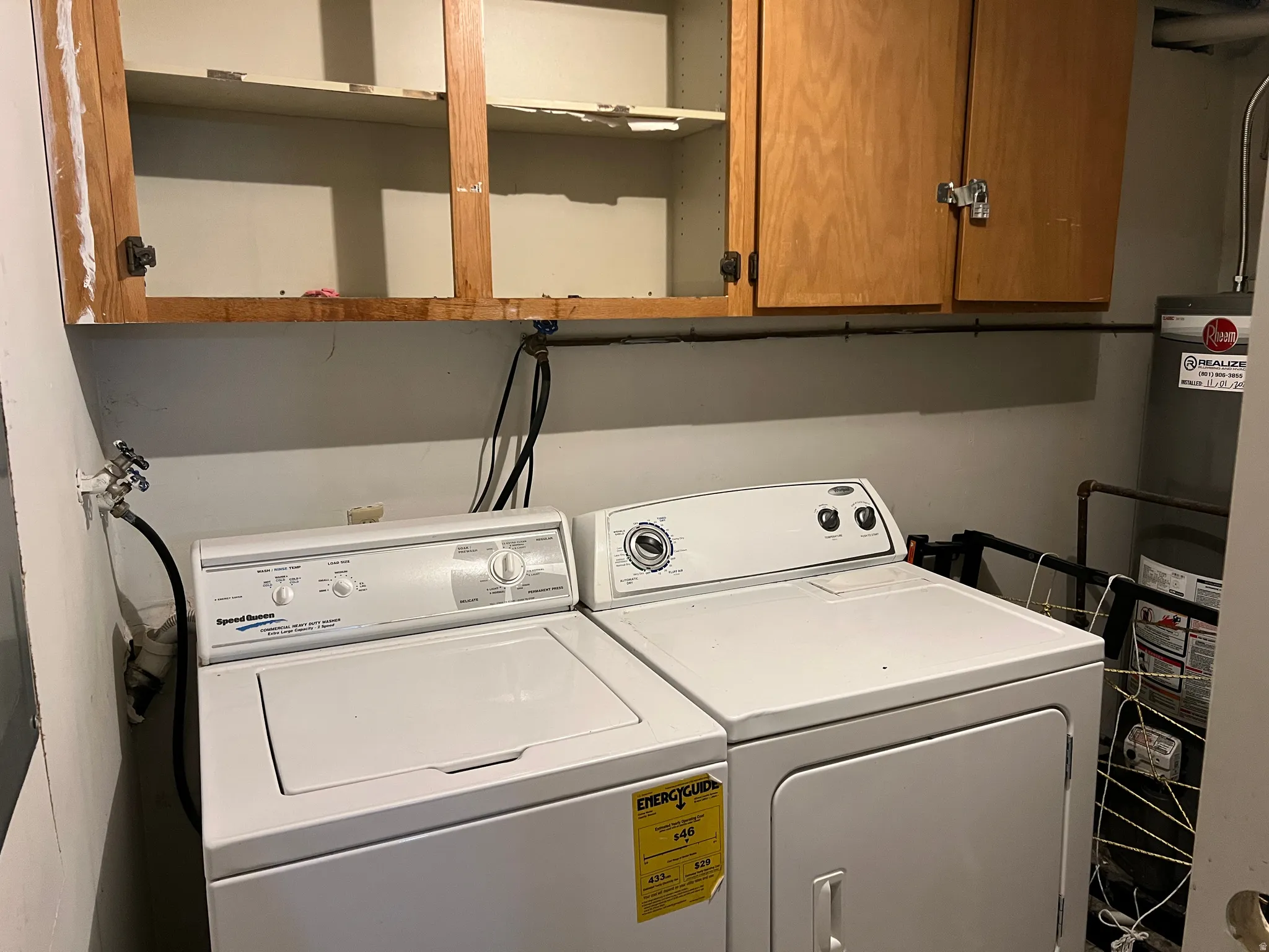 Dedicated laundry area featuring a white washing machine, white dryer, and upper wood-finish cabinetry