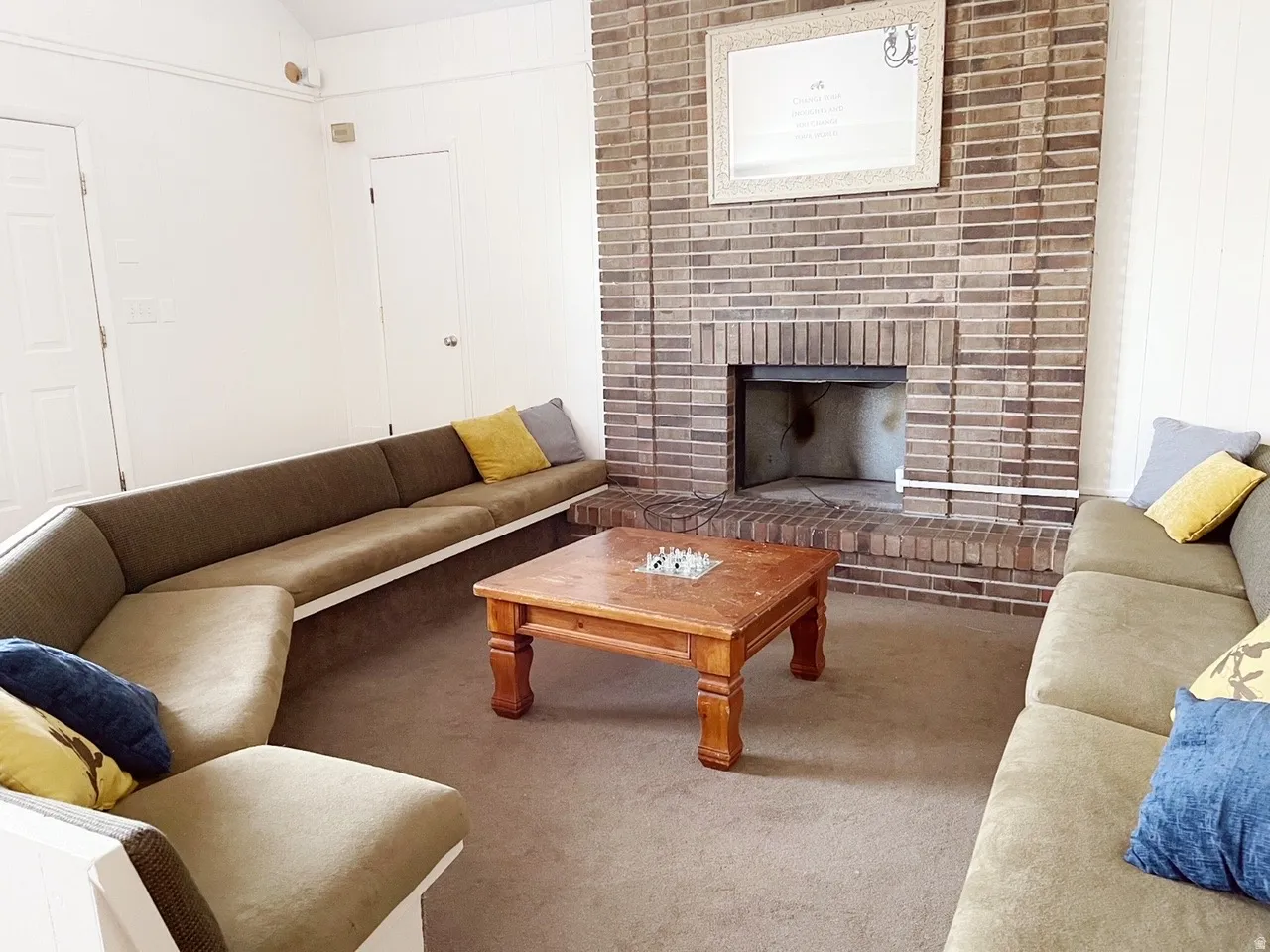 Spacious living area featuring an expansive brick fireplace with a raised hearth