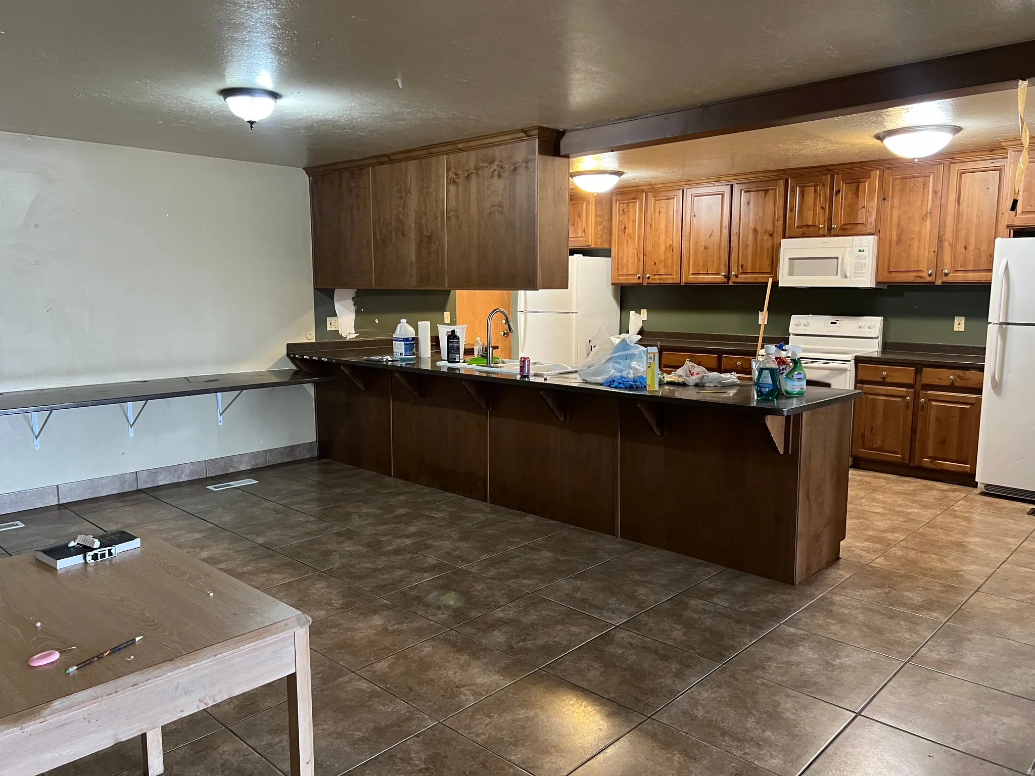 Spacious kitchen featuring extensive wood cabinetry, dark countertops, a built-in oven with overhead microwave, and a substantial central island