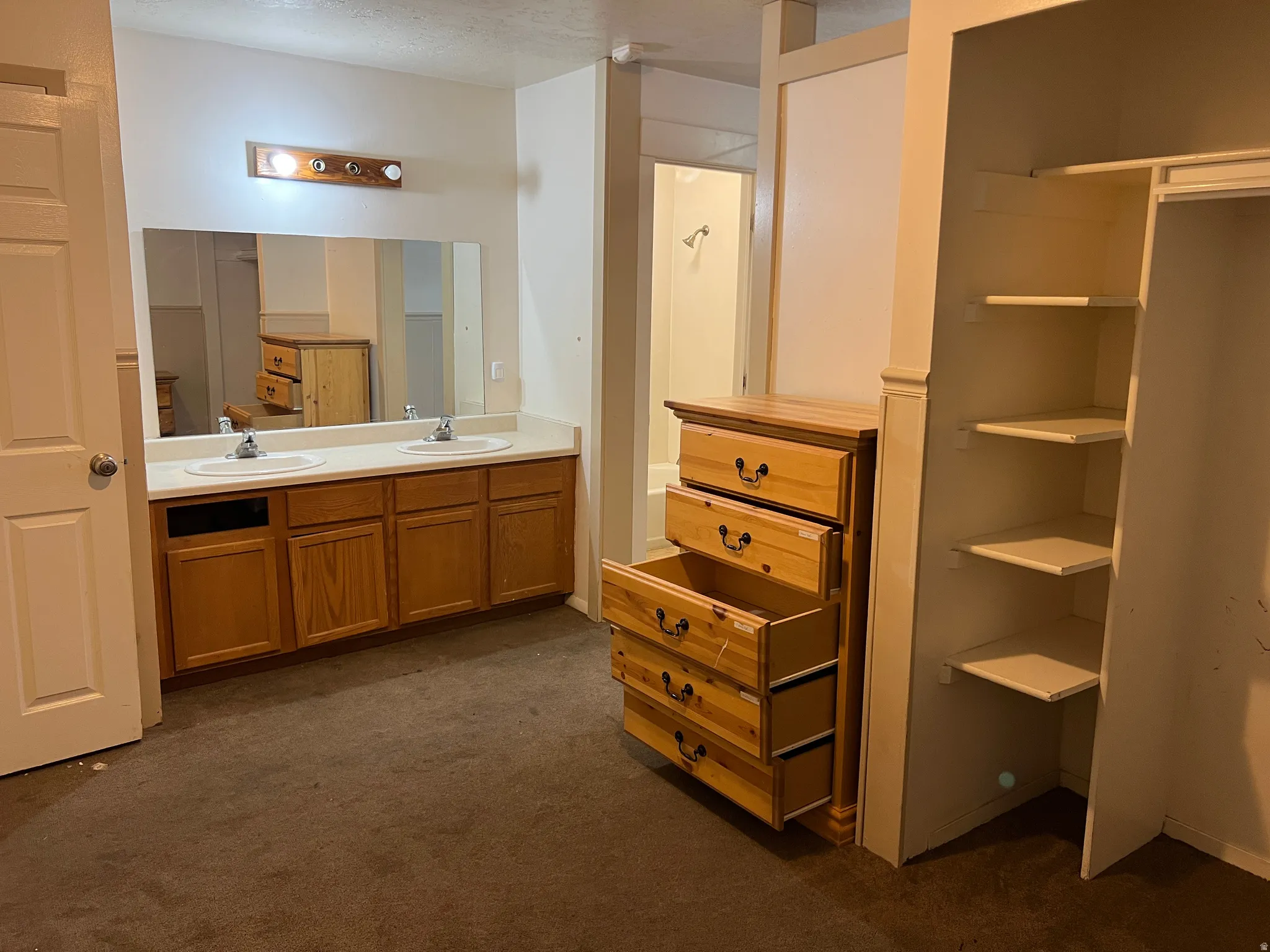 Bathroom vanity with dual sinks, a large mirror, and overhead lighting