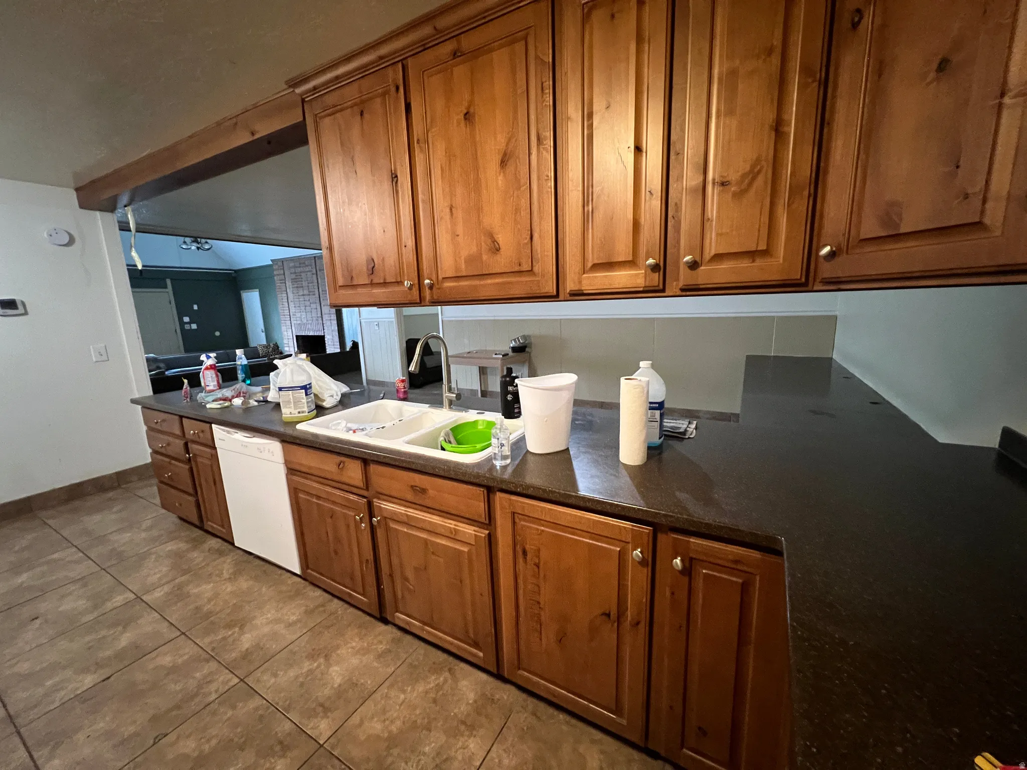 Kitchen featuring wood-finish cabinetry, dark countertops, and a double basin sink with a chrome faucet