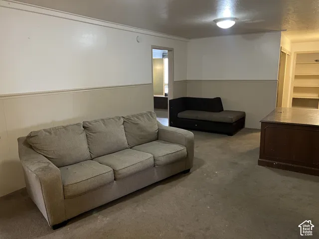 Carpeted interior space featuring two-tone walls with wainscoting and crown molding, and a flush mount ceiling light fixture