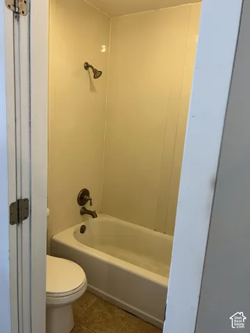 Bathroom featuring a white bathtub, bronze-finish shower fixtures, and a white toilet