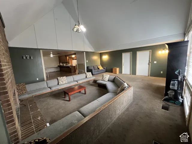 Spacious living area featuring a vaulted ceiling and exposed brickwork