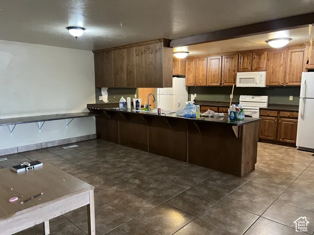 Spacious kitchen featuring extensive wood cabinetry, dark countertops, a built-in oven with overhead microwave, and a substantial central island