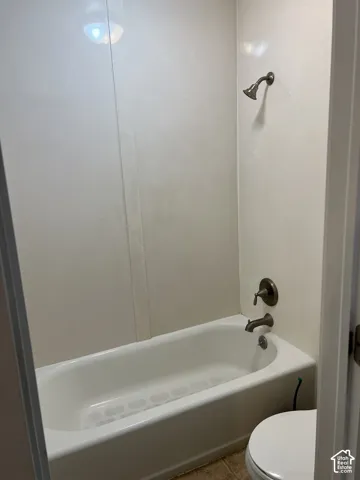 White bathtub and shower combination with a bronze-finish showerhead and faucet
