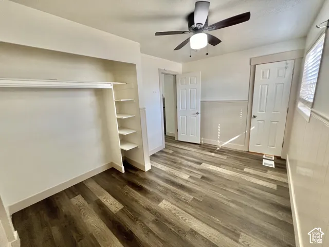 Room featuring wood-finish flooring, a built-in closet with shelving, a ceiling fan with integrated lighting, and white paneled doors