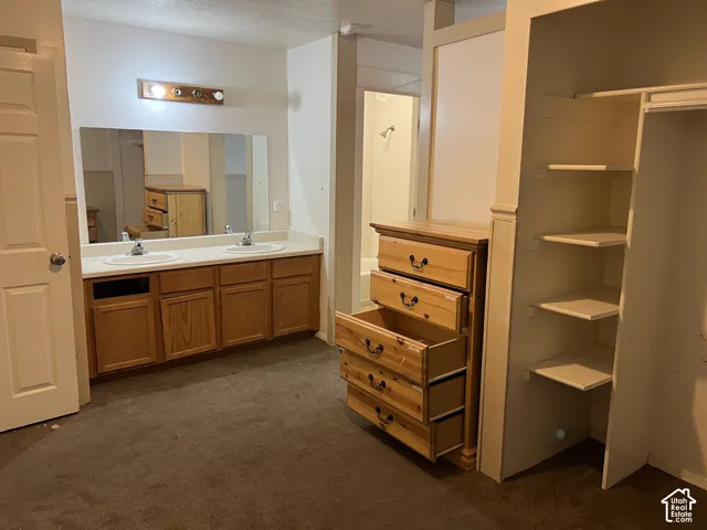 Bathroom vanity with dual sinks, a large mirror, and overhead lighting