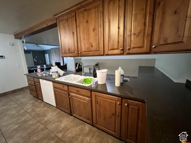 Kitchen featuring wood-finish cabinetry, dark countertops, and a double basin sink with a chrome faucet