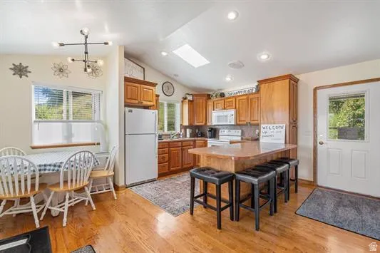 Kitchen area featuring wood-finish flooring, wood cabinetry, a central island with seating, a skylight, and recessed lighting