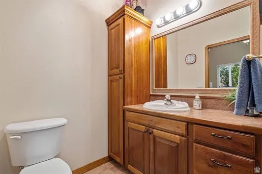 Bathroom featuring a large vanity with an integrated sink, a spacious mirror with a wood frame, and a tall built-in storage cabinet