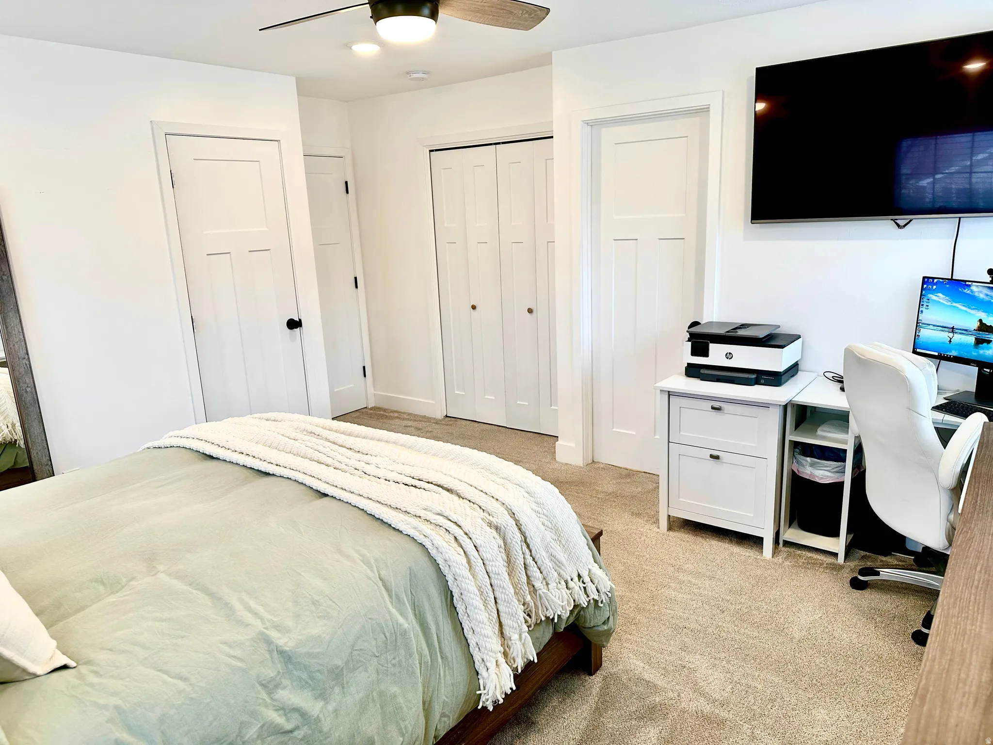 Carpeted room featuring a ceiling fan with integrated lighting, white shaker-style doors, and bi-fold closet doors