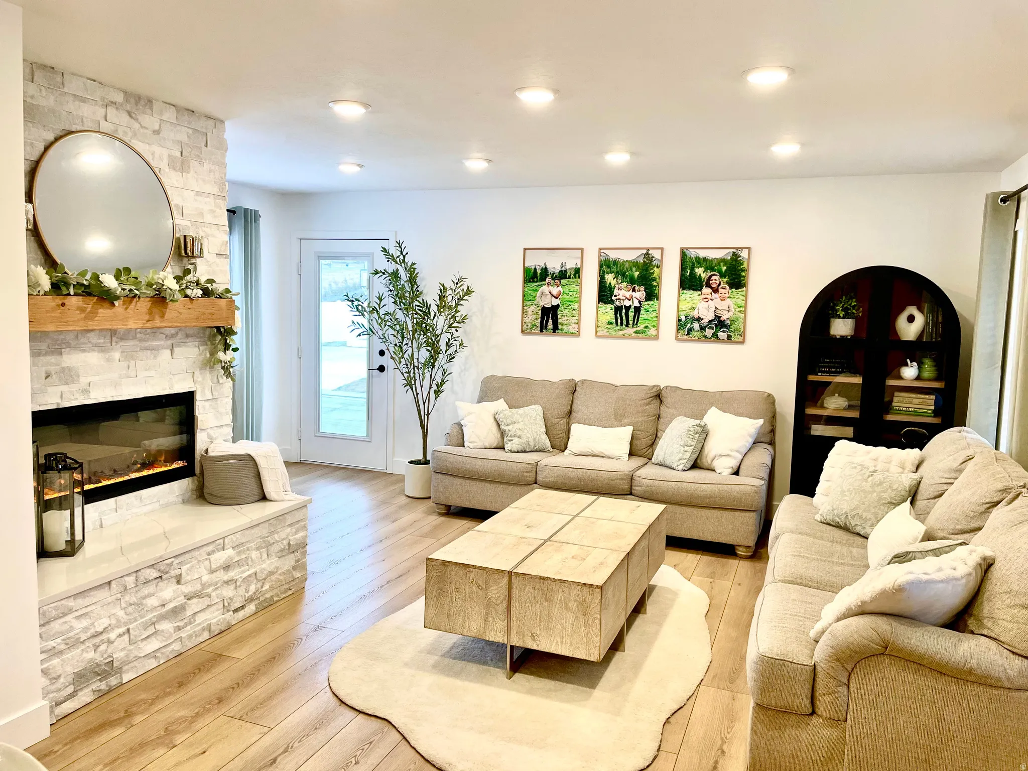 Living area featuring a floor-to-ceiling stacked stone fireplace with a wood mantle, wood-finish flooring, recessed lighting, and a glass-paneled exterior door