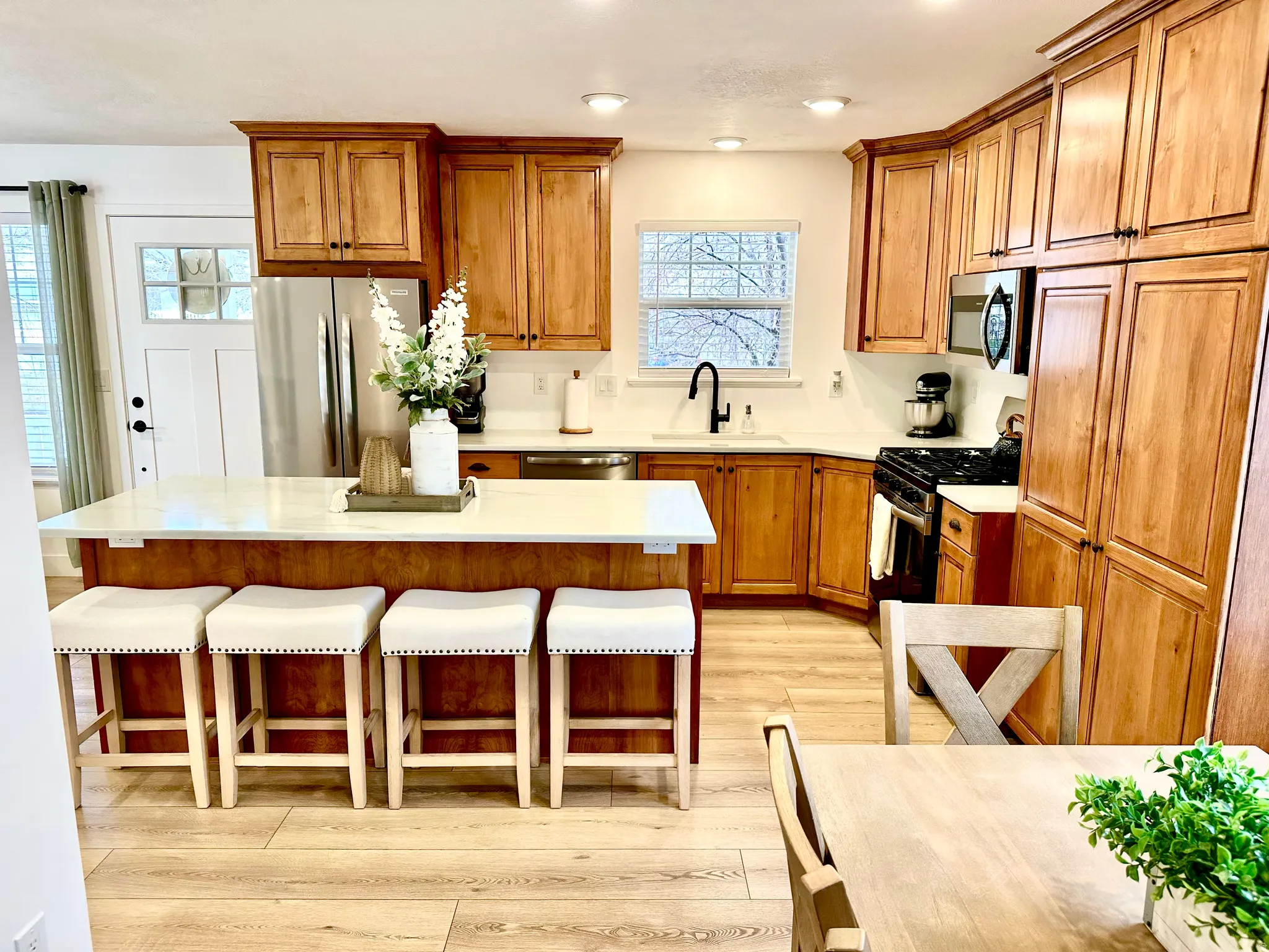 Kitchen featuring wood-finish cabinetry, stainless steel appliances, a center island with countertop seating, recessed lighting, and wood-finish flooring