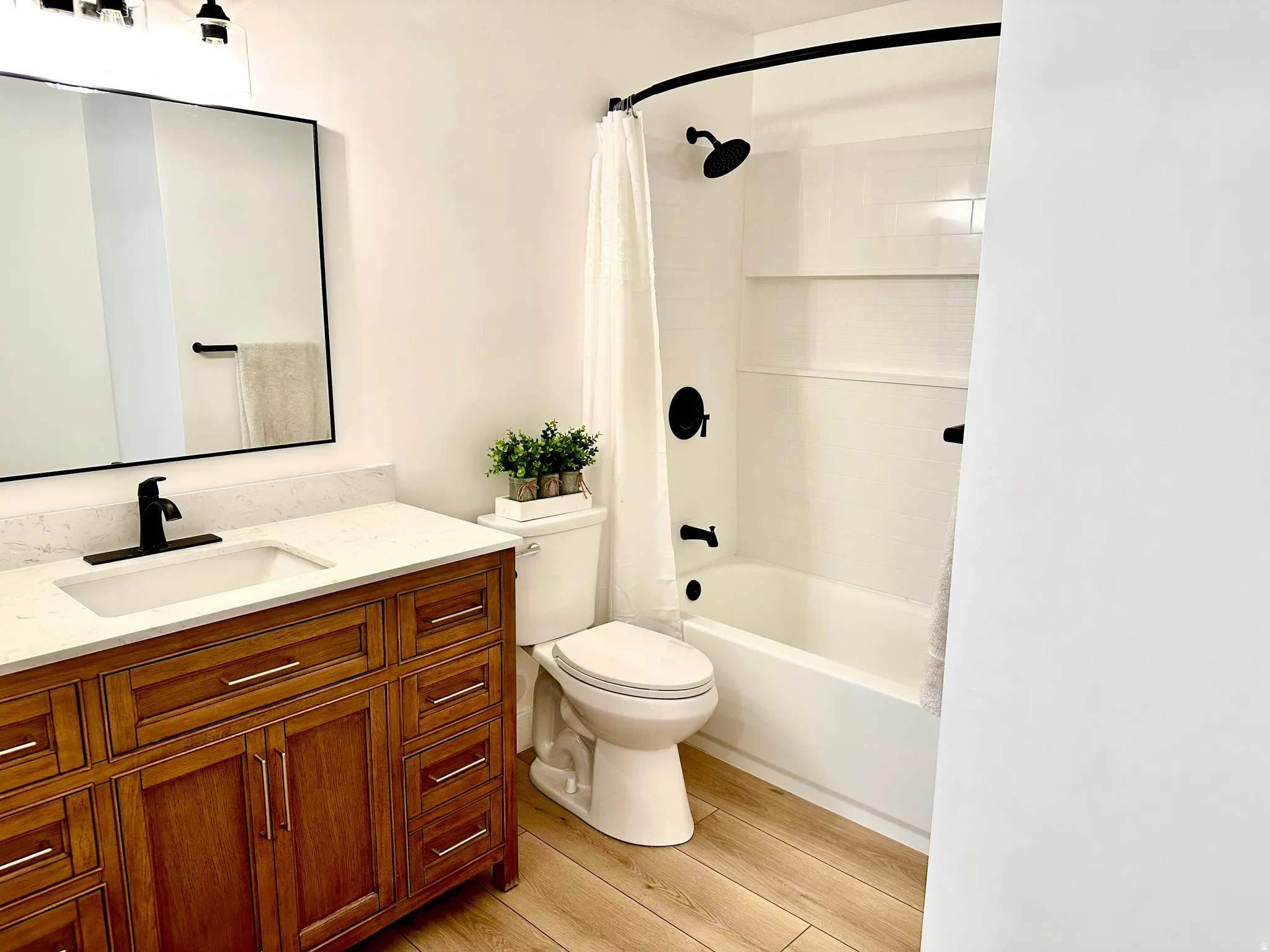 Bathroom featuring a wood-finish vanity with a light-toned countertop, integrated sink, and black hardware