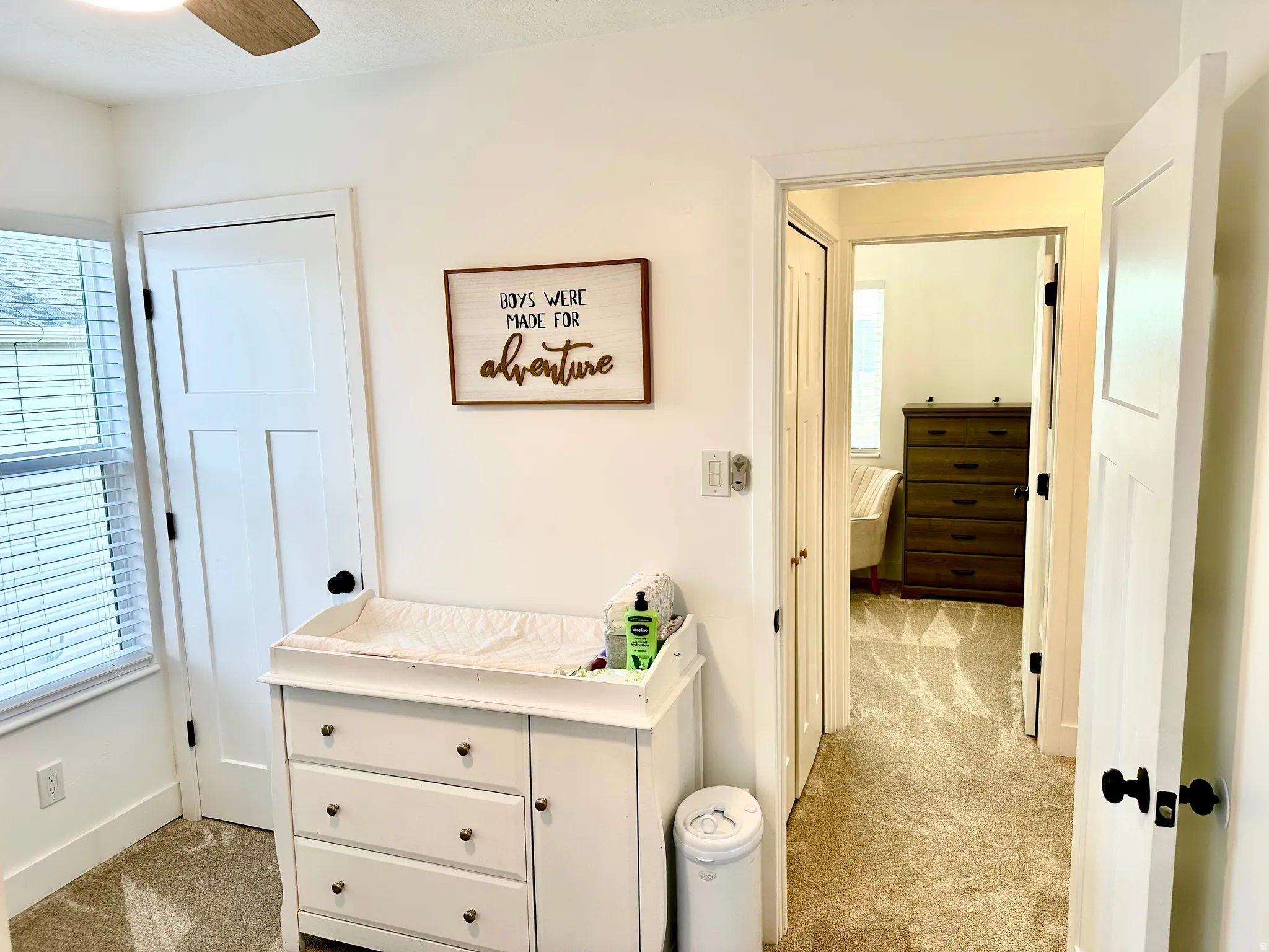 Interior room featuring a ceiling fan, window with blinds, and white panel doors with black hardware