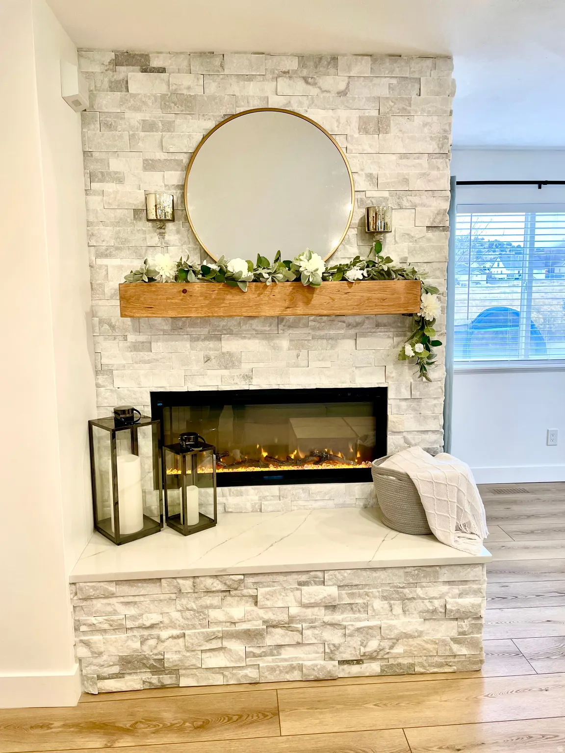 Stacked stone fireplace featuring an integrated electric firebox, a solid wood mantel, and a stone hearth
