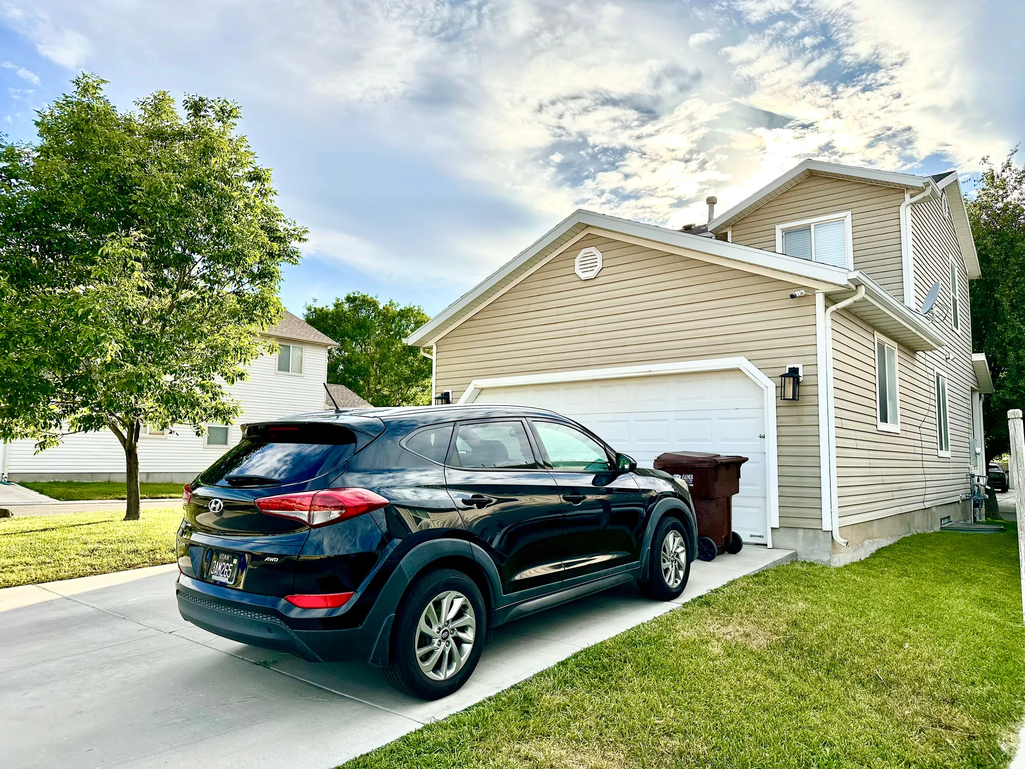 Two-story residence featuring light-toned horizontal siding, a white garage door, and a concrete driveway