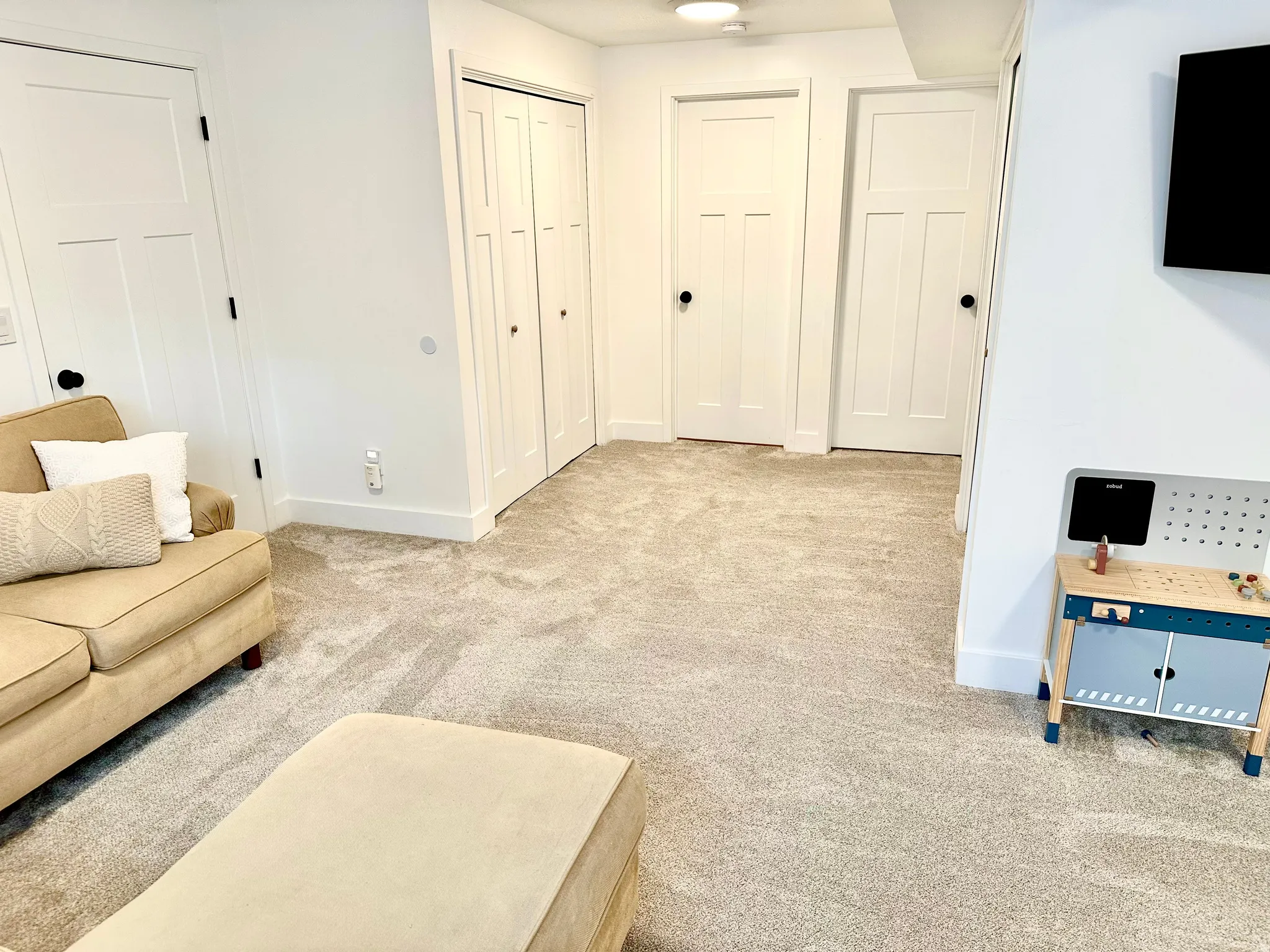 Neutral carpet flooring throughout a room featuring white walls and white trim