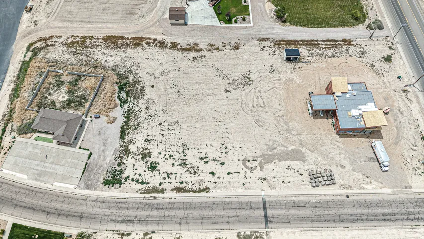 Expansive vacant lot featuring a partially constructed structure with roofing materials