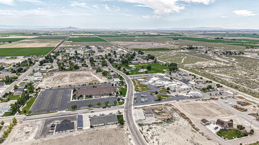 Expansive aerial perspective showcasing a rural community with surrounding agricultural fields and distant mountain ranges