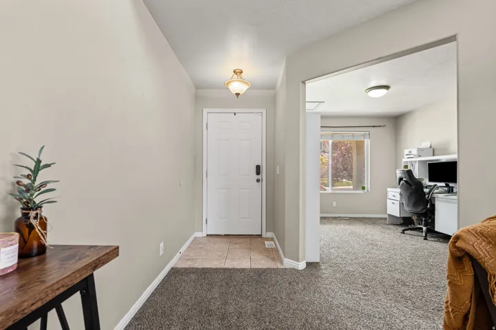 Entryway featuring a paneled door with hardware, overhead light fixture, and tile flooring