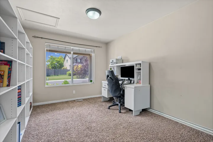 Room featuring extensive built-in shelving, a large window, neutral wall paint, and textured carpeting