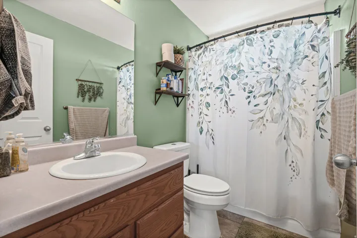 Bathroom featuring a wood-finish vanity with a light-toned countertop and an integrated sink