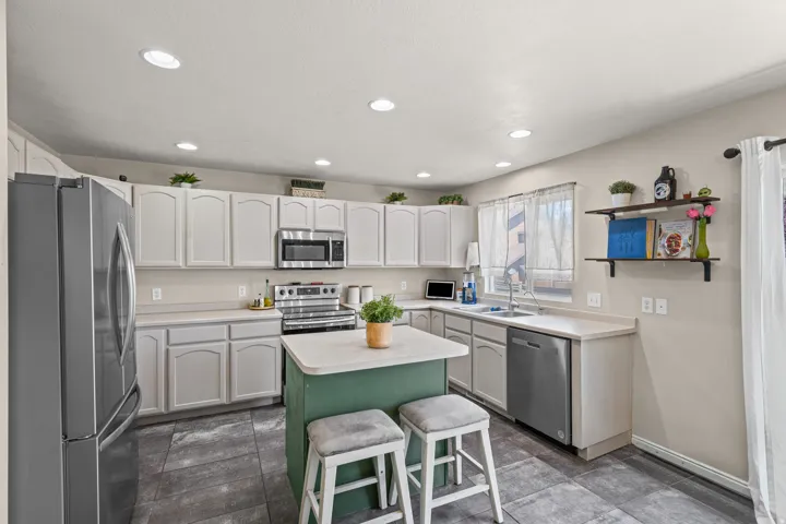 Kitchen featuring light-toned cabinetry, stainless steel appliances, and a central island with a contrasting base