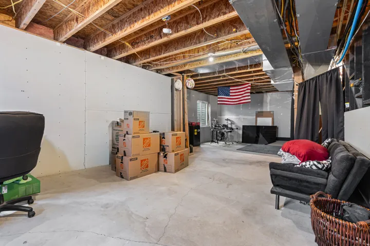 Unfinished basement space with exposed wood joists, concrete flooring, and partial drywall installation