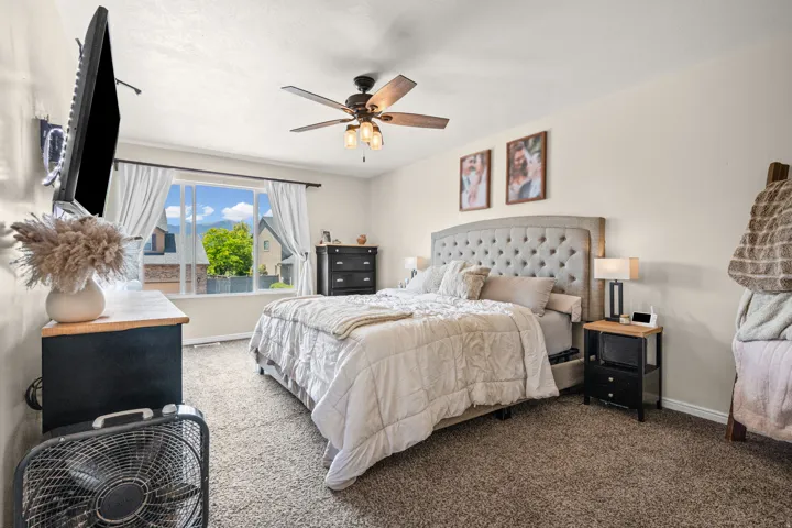 Carpeted room featuring a large window, a ceiling fan with integrated lighting, and neutral wall tones